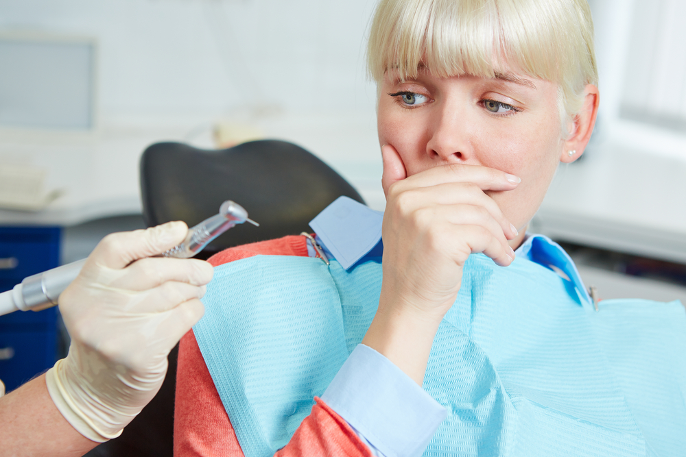 Woman At Dental Practice Refusing Dentist Treatment With Her Hand
